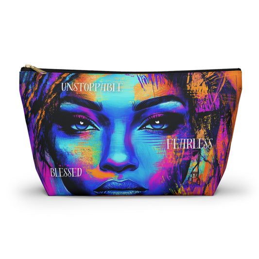 A vibrant accessory pouch featuring a bold portrait of a woman with empowering words like "Unstoppable," "Fearless," and "Blessed" in striking colors. Available in two sizes.