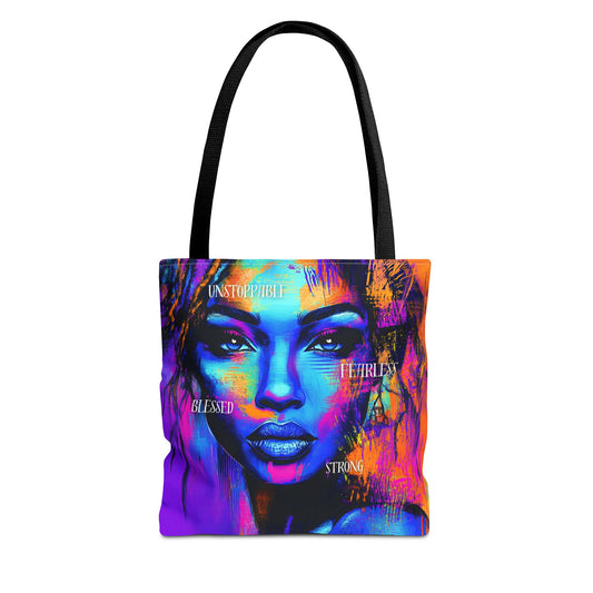 A vibrant tote bag featuring an empowering portrait of a woman, with words like "Unstoppable," "Fearless," "Blessed," and "Strong" in bold colors. Available in three sizes.